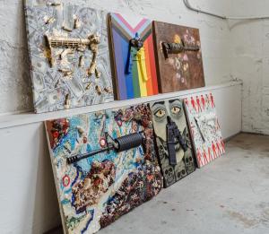 An AR-15 cut into six pieces, transformed by six artists into artistic statements against gun violence. Each unique piece leans against a wall.