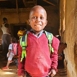 Proud young boy with a new backpack looks forward to his first day of school.