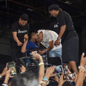 A specially abled fan on a wheelchair cries in joy and disbelief as Ronaldinho and Dybala hug him