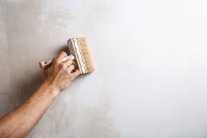person painting over mold white wall with a paint brush