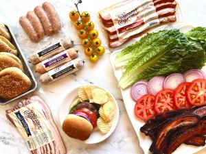 The image includes Ground Bacon, Bacon Strips. Lettuce, Cheese, Tomatoes and Buns to create a Smash Burger!