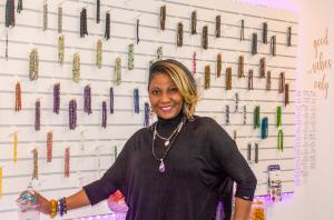 Woman standing in front of bead wall in her store.