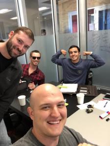 4 guys sitting at a table looking up at the camera man