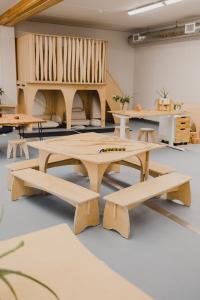 Close up of a classroom equipped with wooden educational furniture, green plants, and pillows and textiles in neutral colours.