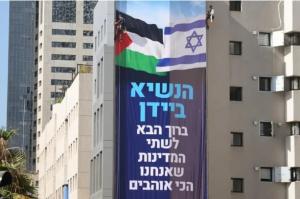 Workers hang a banner on a building in Tel Aviv welcoming President Biden and urging a two-state solution to the Israeli-Palestinian conflict.