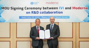 Dr. Kim and Dr. Burton hold up a signed copy of the MOU in front of a banner that says "MOU Signing Ceremony between IVI and Moderna on R&D Collaboration