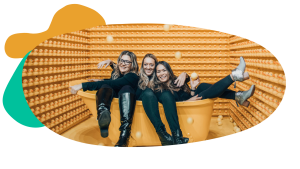 Three employees sit in an oversized bathtub together at an interactive event, laughing.