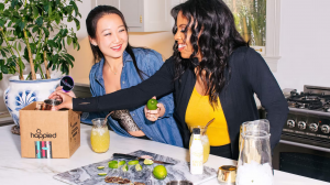April Johnson, Esq. and Sharon Cao enjoy unboxing a Happied virtual event kit on a kitchen counter.