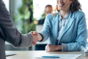 Attractive real-estate agent shaking hands with woman after signing agreement contract
