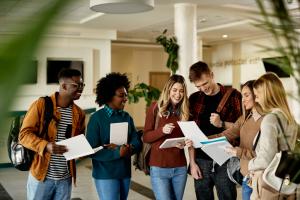 Group of happy students looking at exam results while standing at university hallway