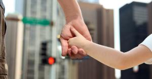 Parent and child holding hands at an intersection