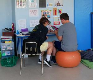 FireFly Autism team member working with student at a desk