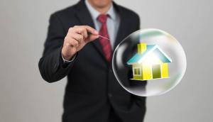 Man in a suit holding a needle over a bubble containing a house