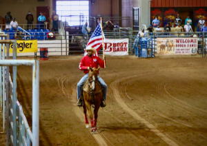 Photo of a Black cowboy riding with an American flag at the Arizona Black Rodeo in 2021.