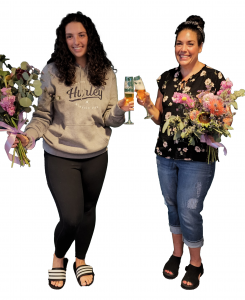 Two woman cheers glasses holding flowers at Peoria Florist Bouquet & Bubbles Vistancia Peoria, AZ event