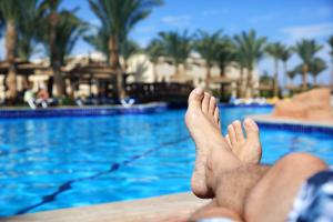 Man's legs lying down on a sun lounger looking over the water