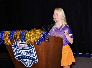 Girl with blonde hair, purple Tigers shirt, and orange skirt at College Football Hall of Fame podium