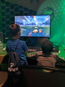 Two young gamers play Rocket League at one of Unified's quest desks.