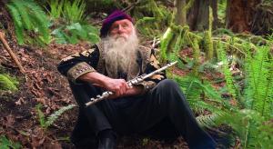 Dean Evenson sitting in nature with his flute.