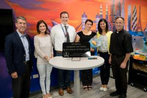 Staff standing with a dedication plaque, facing forward
