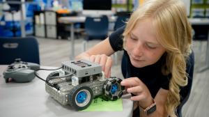 Student leaning over a table working on her car project