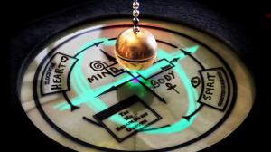 A weighted brass ball suspended from a metal chain, used to magnify the minute movements of the person holding it.