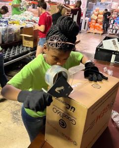 Embrace Girls Foundation member packs boxes of hurricane relief supplies at GEM headquarters