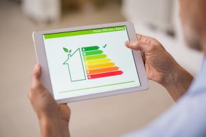 Hand holding digital tablet and looking at house efficiency rating