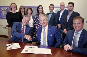 Avila President Jim Burkee (center), Bruce Ranney, president (left), and Joseph Mroz (right), executive vice president of K-12 Teachers Alliance sign the partnership agreement, joined by Avila University leadership team