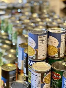 Stacked canned goods, like corn, green beans, kidney beans, peas, and others.