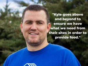 Kyle Jackson wears a blue shirt and stands in front of trees