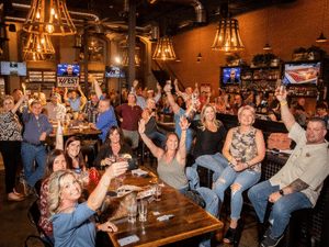 big group photo of 12 West patrons raising their glasses