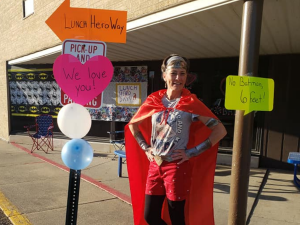 Rachelle Wuellner wears a cape and stands outside her school