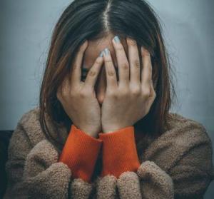 Young woman, hands covering face