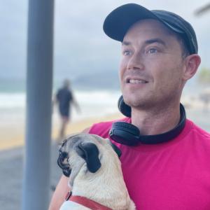 Adam Cox at the beach with a puppy that is a small 12 poud pug named cindy crawford (after the supermodel) after recently completing studies at Harvard Business school, but before beginning his studies of Business Law at Cornell