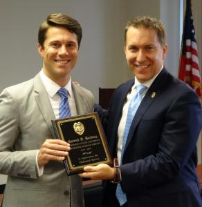 Attorney Garrick Harding standing with a plaque given by State Attorney Dave Aronberg in Palm Beach County.