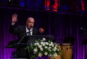 Oscar Hernandez, pianist and musical director of the award-winning Spanish Harlem Orchestra on stage receiving the Compañero Award, a brightly colored ceramic figure of a half sun and moon, at the Cielo Gala.