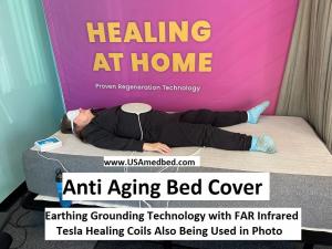 A woman lays down on the Anti Aging bed Cover while using the Tesla healing paddles