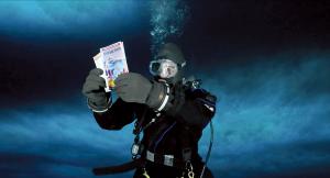 Dr. Thurber reading "Antarctica!" while scuba diving beneath the sea ice.