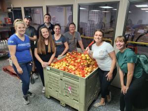 8 Midland team members stand around a large crate holding 1,400 bags of apples.