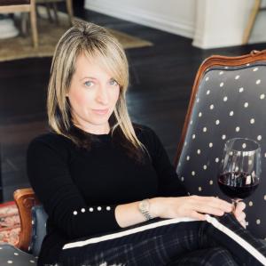 Woman sits in an armchair chair holding a glass of red wine