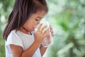 Little girl drinking clean water with a natural background