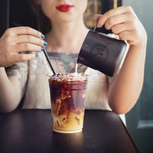asian woman pouring milk into a Mikah coffe cup