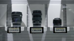 Camera lenses for sale are on display on the Foto Ruano showroom with Newton Digital Labels. The digital labels' screens are designed to match Foto Ruano's branding to aesthetically display the lenses' prices and product information.