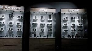The photo shows part of the Foto Ruano showroom where three display cabinets are standing, one for Nikon cameras, one for Lumix cameras, and another one for Olympus OM System cameras.