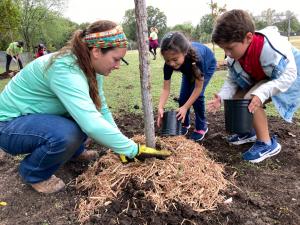 Urban Forester Tara Nathanson helps first graders mulch around a newly planted tree