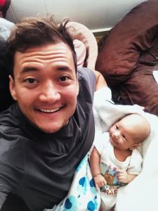 Danny the Doula smiles as he cares for his client's newborn while she catches up on sleep.