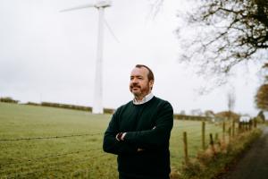 Photo of Michael Thompson, managing director, Everun, a renewables firm in Northern Ireland. Michael is standing outside a wind turbine.