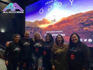 Six people wearing All4Access shirts stand in front of a movie screen projecting a Good Night Oppy image. 