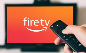 A hand holds a remote in front of a TV with Amazon Fire streaming service logo on the screen. Local lawyers who use television advertising have to adjust their law firm marketing strategies to the spread of streaming TV.